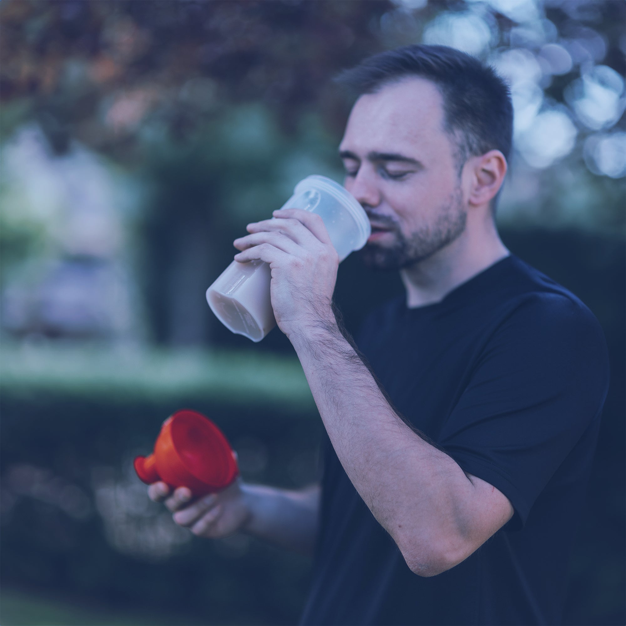 Man Drinking from what appears to be a Protein Mixer Cup