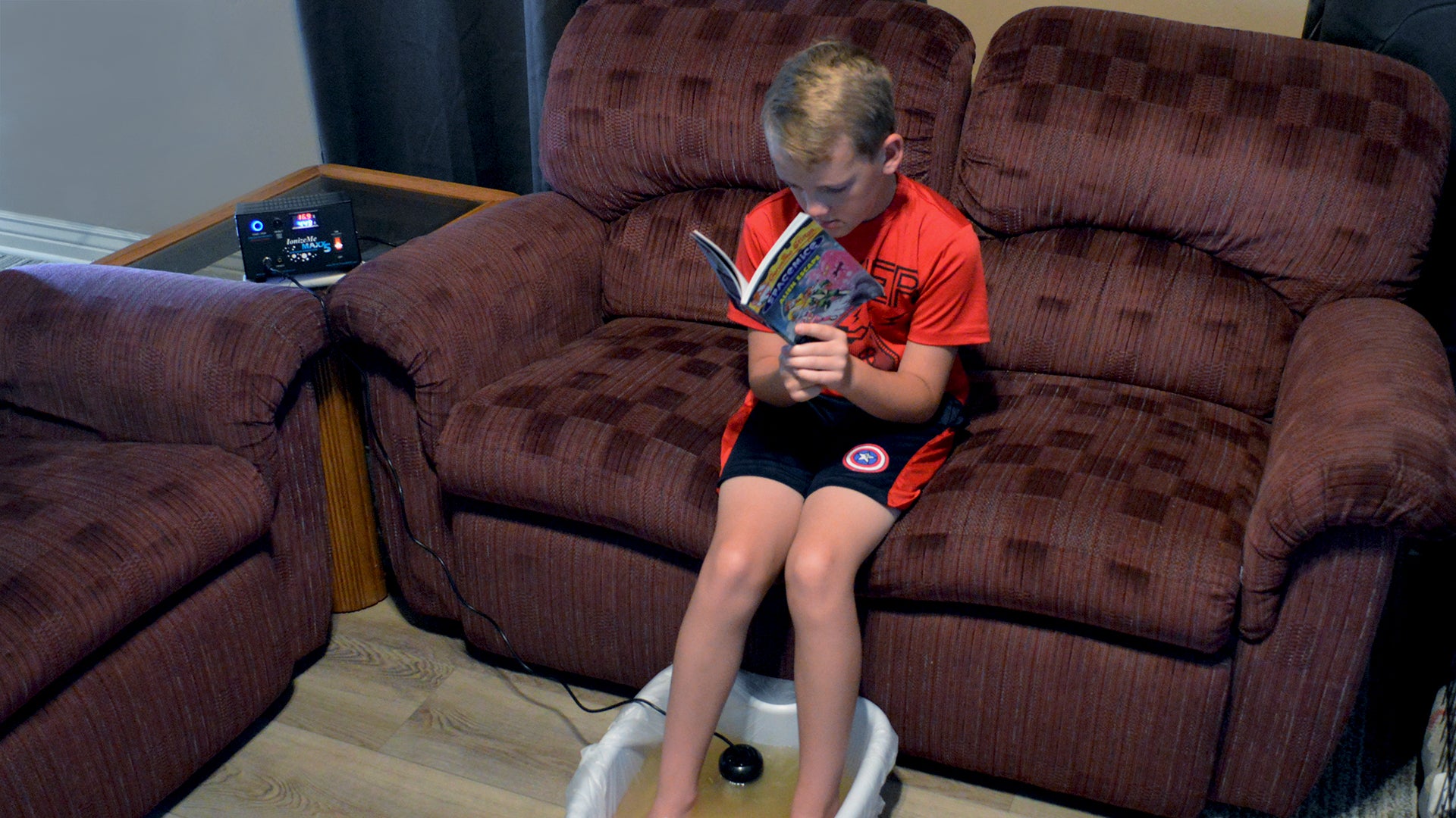 Child taking a ionic foot detox while reading a book.