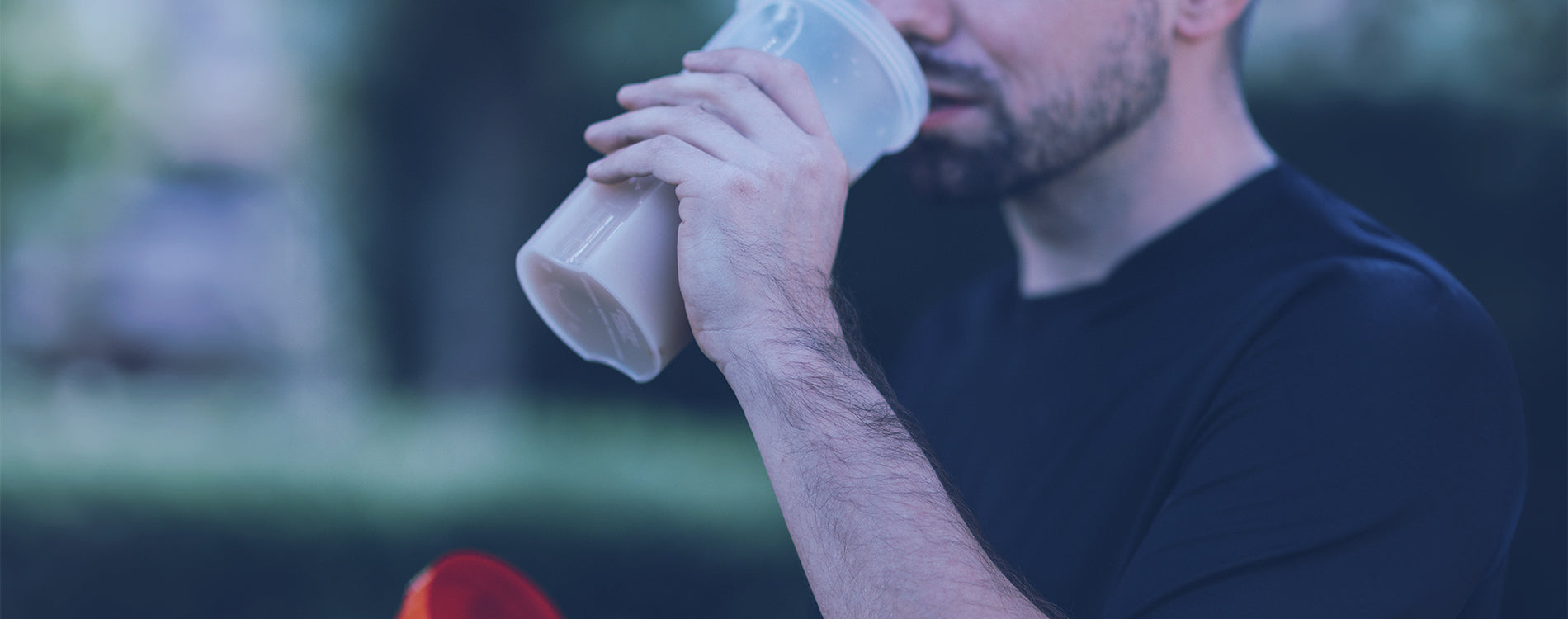 Man Drinking from what appears to be a Protein Mixer Cup