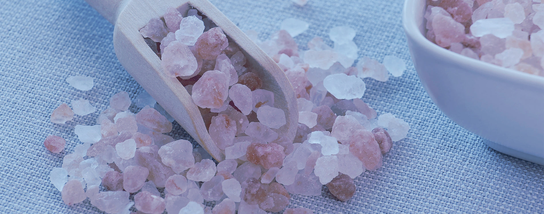 Himalayan Sea Salt Chunks on a linen cloth.  There is a scoop with some of the salt in it and a bowl that has more salt in it as well.