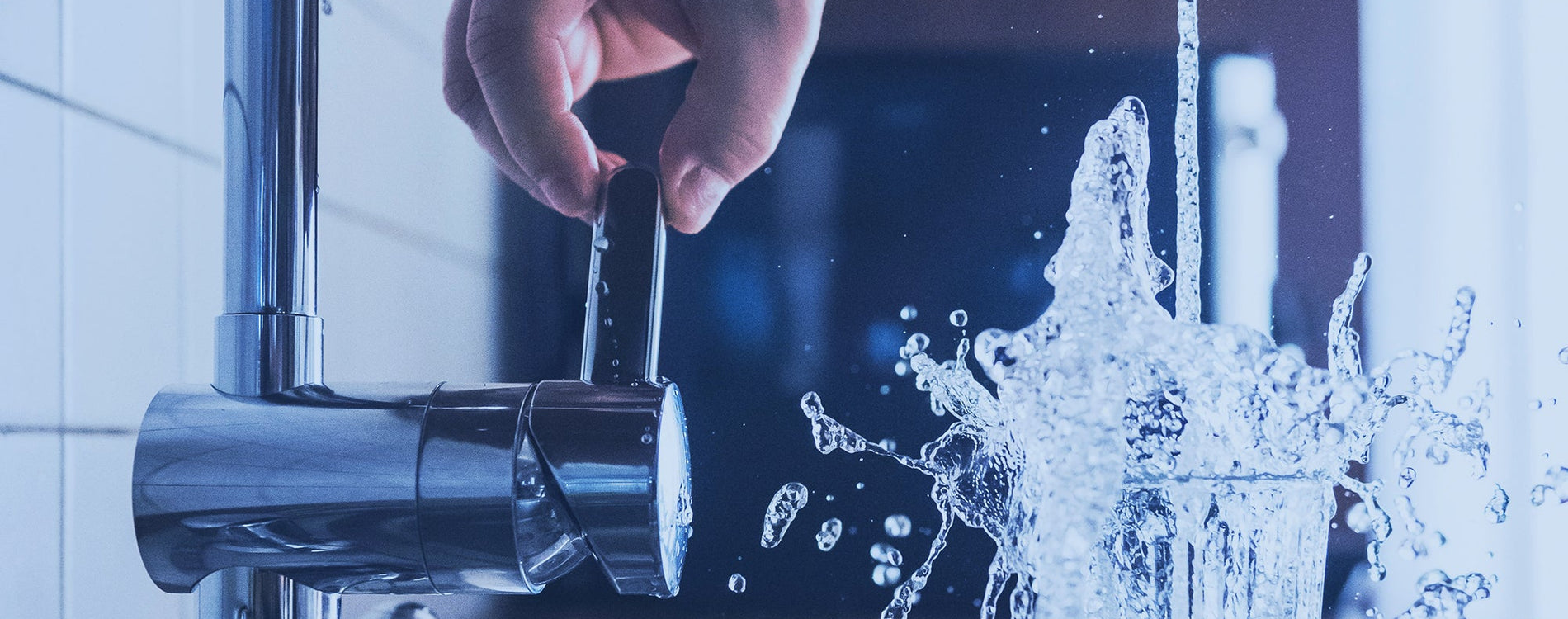 What looks like a fellows hand turning on a sink to fill up a glass of water. The water is splashing out of the glass.