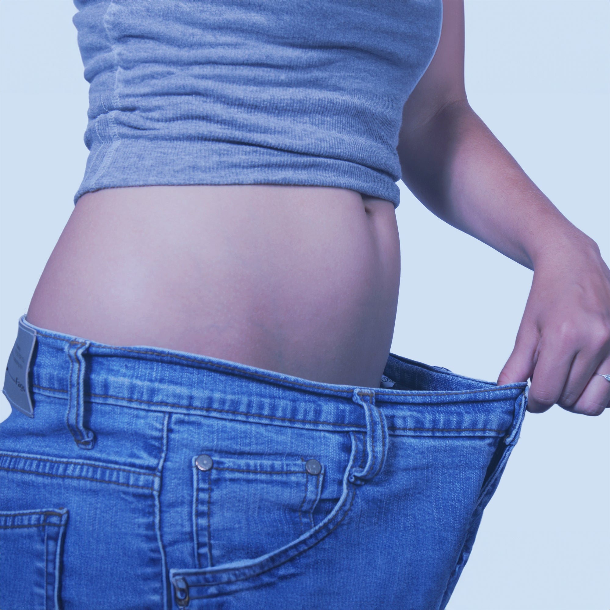 A woman showing her belly while wearing a much larger sized pair of pants and pulling on the extra length in the waist as if she has lost that much weight.