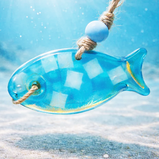 Blue glass fish ornament with rope against a beach background