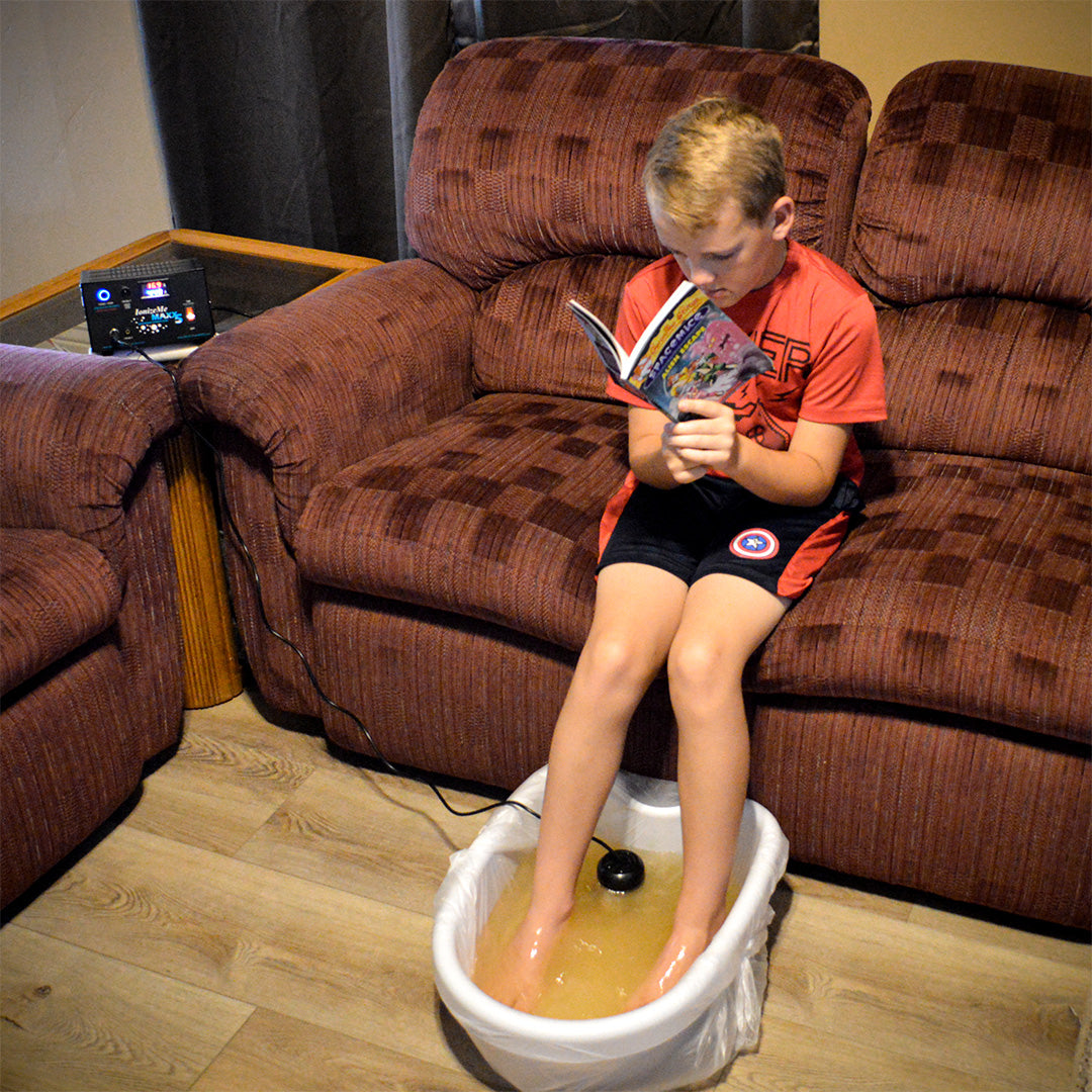 Child doing Ionic Foot Detox with the IonizeMe Maxx 5 while reading a book