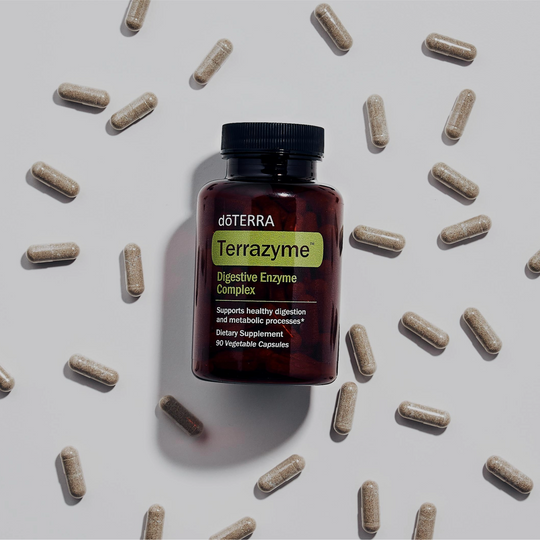 doTERRA Terrazyme digestive enzyme complex bottle surrounded by capsules on a light gray background