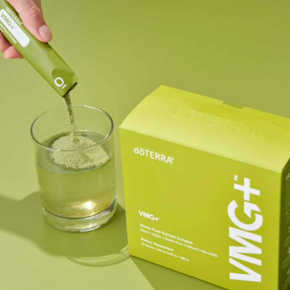 doTERRA VMG+ supplement being added to a glass with a green background